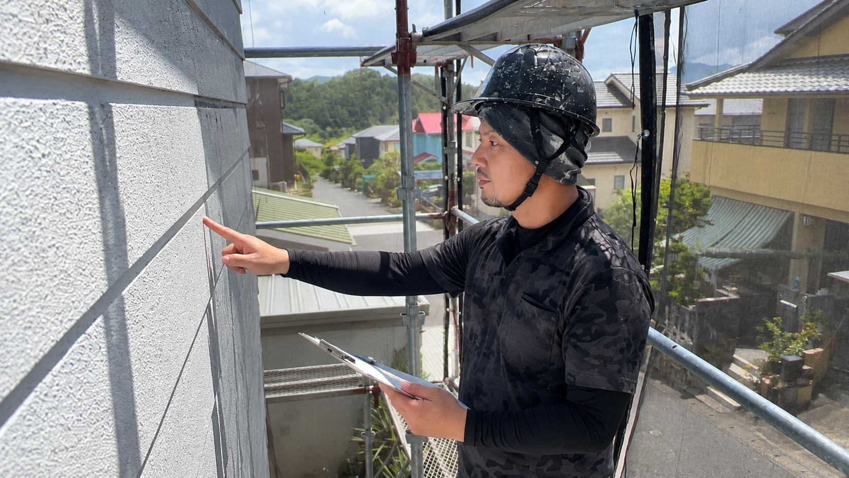 現地調査中に外壁を指差す職人